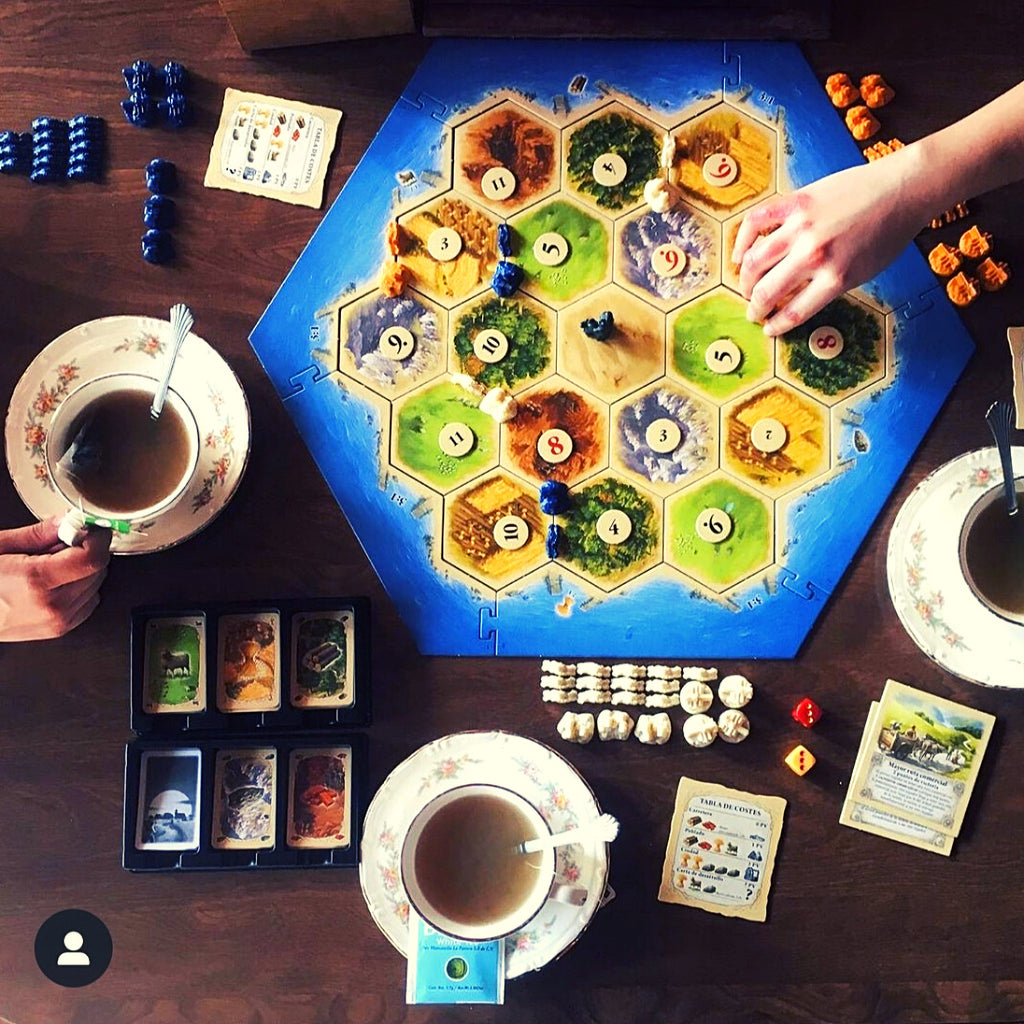 sipping on tea and playing catan board game, top down shot