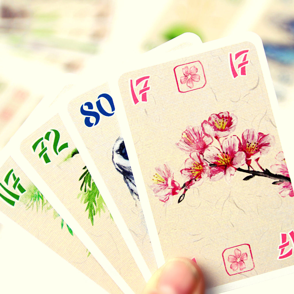 a hand of beautiful cards, cherry vlossoms, water, greenery