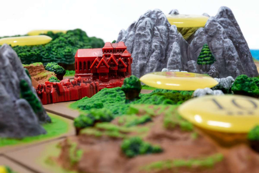 Catan Studio Catan 3D Edition board game road and city in a valley beside two mountains