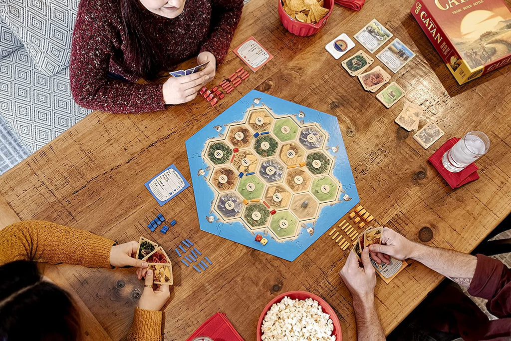 top down view of three friends playing catan board game