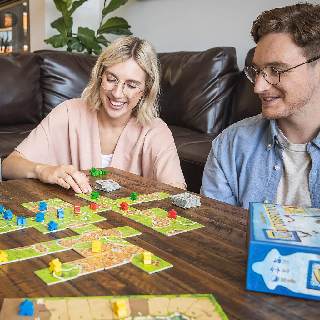 young couple playing board game Carcassonne on a brown club table